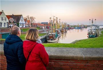 Touristen schauen auf die Krabbenkutter am Hafen.