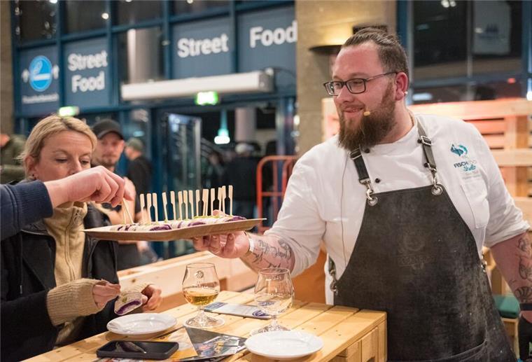 Fischsommelier Ralf Harms reicht Teilnehmern im Fischkochstudio Bremerhaven Häppchen.