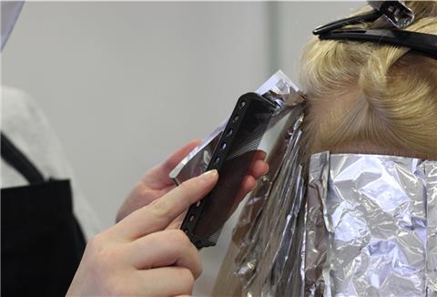 Eine Friseurin arbeitet mit einem Kamm an einem Modellkopf.