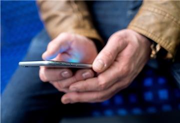 Ein junger Mann sitzt in einer S-Bahn und benutzt dabei sein Smartphone. 