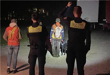 Polizisten und Helfer mit einem Suchhund sind auf einem Parkplatz unterwegs.