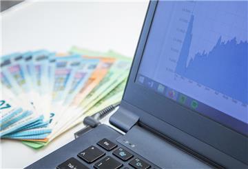 Geldscheine und Laptop auf einem Tisch. ETFs sind günstig und breit gestreut – ideal für die Altersvorsorge. Die Verbraucherzentrale erklärt, welche Strategien für Einsteiger sinnvoll sind.