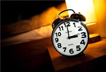 Eine Uhr steht neben einem Bett.