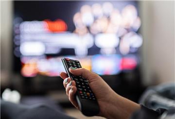 Eine Hand hält eine Fernbedienung vor einem SmartTV. SmartTVs sammeln viele Daten der Nutzer. WIr zeigen, was man dagegen tun kann.