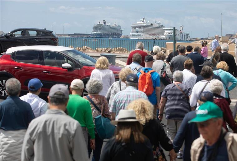 Massentourismus-Gefahr: Vermeidet im Sommer diese Urlaubsziele Menschen und Fahrzeuge überqueren einen Zebrastreifen vor dem Hafen von Palma, wo Kreuzfahrtschiffe vor Anker liegen.