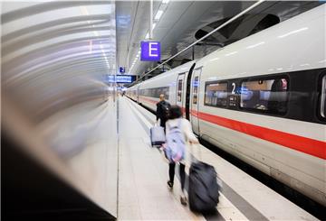 Fahrgäste gehen am Berliner Hauptbahnhof an einem ICE entlang.