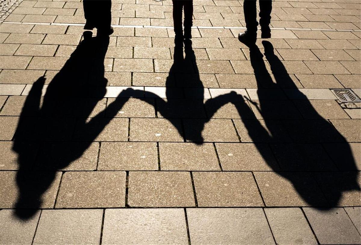 Bis zu 297 Euro monatlich pro Kind! Diese Familien haben Anspruch auf den Kinderzuschlag Die Schatten von zwei Erwachsenen und einem Kind fallen in den Morgenstunden auf den Asphalt.