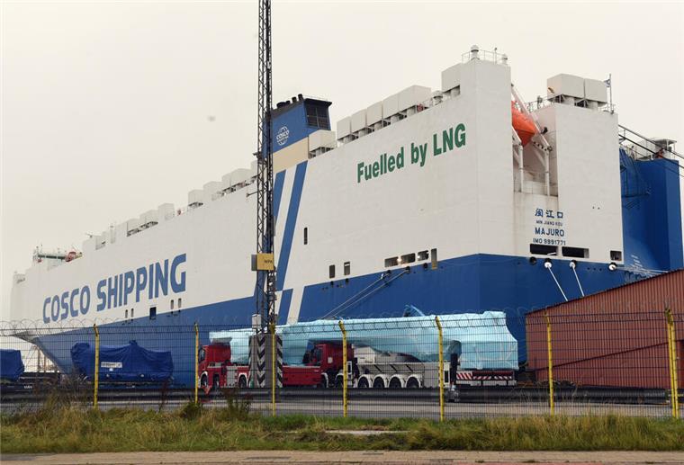 Blau-weißer Autotransporter mit dem Namen der Reederei "Cosco Shipping" und dem Schriftzug "Fuelled by LNG" liegt im Hafen.