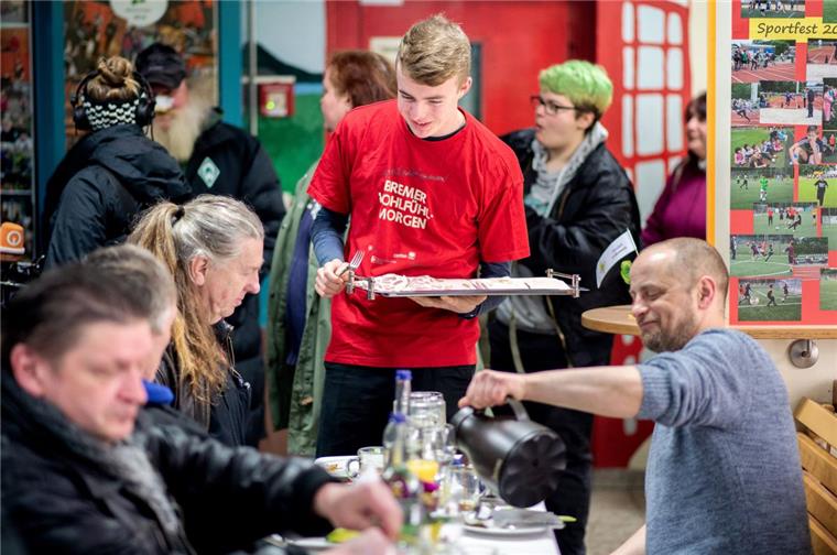 Felix Ellerhorst, freiwilliger Helfer, verteilt während des Frühstücks im Rahmen des Bremer "Wohlfühlmorgens" in der St.-Johannis-Schule Aufschnitt an die Gäste. 