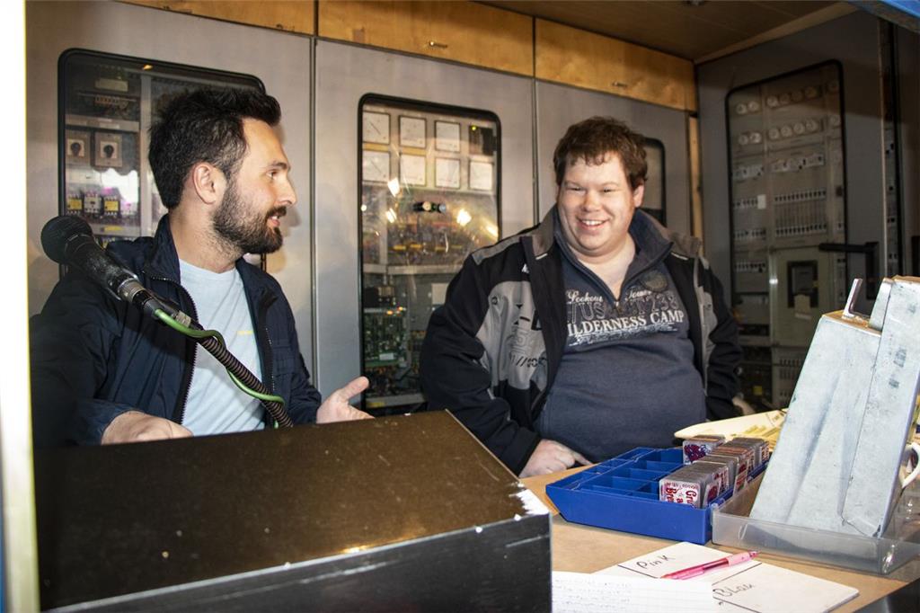 Felix Verspermann (links) erklärt den Fahrerstand eines Karussells.