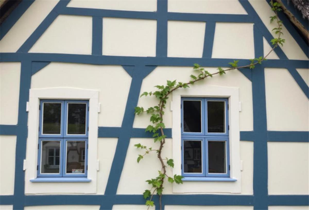 Die unsichtbare Sanierung: Wie Fensterfolien den Wohnkomfort in Norddeutschlands Häusern steigern Ein Fachwerkhaus mit blauen Fensterrahmen und Fensterfolie.