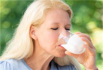 Eine Frau trinkt ein Glas fermentierter Milchprodukte.
