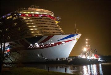 Zuschauer stehen auf dem Deich vor dem neuen Kreuzfahrtschiff «Iona», das von einem Schlepper von der Meyer-Werft in die Ems gezogen wird.