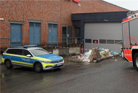 Feuerwehr und Polizei sind vor der Müllpresse eines Supermarkts im Einsatz. 