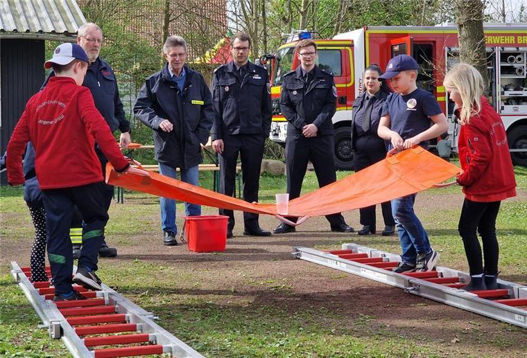 Feuerwehrdezernent Stadtrat Peter Skusa schaut sich zusammen mit dem Jugendfeuerwehrwart Jan Haucke und den Organisatoren Nathalie Zander und Thies Renken gespannt eine Station der Kinderflamme an.