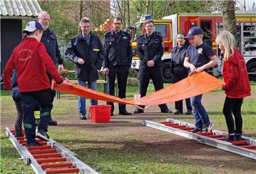 Feuerwehrdezernent Stadtrat Peter Skusa schaut sich zusammen mit dem Jugendfeuerwehrwart Jan Haucke und den Organisatoren Nathalie Zander und Thies Renken gespannt eine Station der Kinderflamme an.
