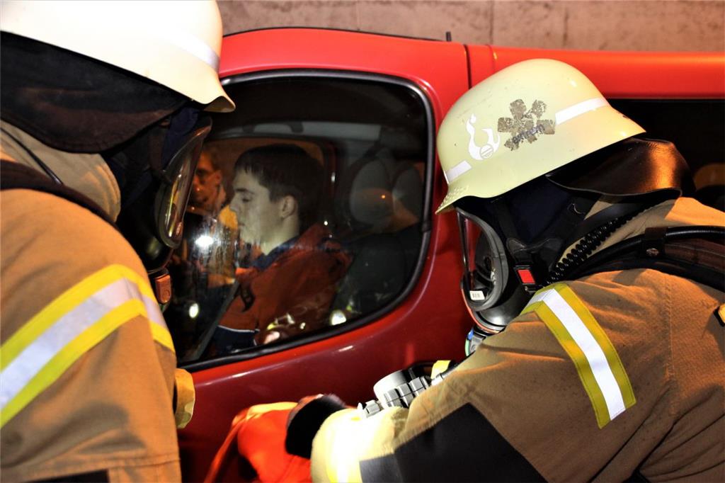Feuerwehrkräfte versuchen einen noch in einem Fahrzeug sitzenden Verletzten anzu...