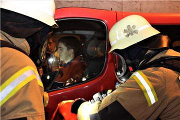 Feuerwehrkräfte versuchen einen noch in einem Fahrzeug sitzenden Verletzten anzu...