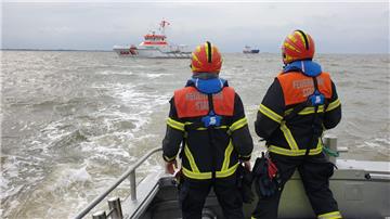 Feuerwehrleute auf der "Henry Köpcke" blicken auf die Einsatzstelle.