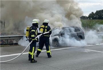 Das Foto zeigt Feuerwehrleute beim Löschen des brennenden Fahrzeugs.  