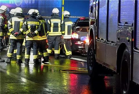 Feuerwehrleute stehen nach einem Unfall auf der Fahrbahn