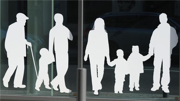 Figuren von Menschen in verschiedenem Alter sind auf Fensterscheiben aufgeklebt.
