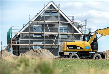 Ein Bagger steht vor dem Neubau eines Eigenheims.