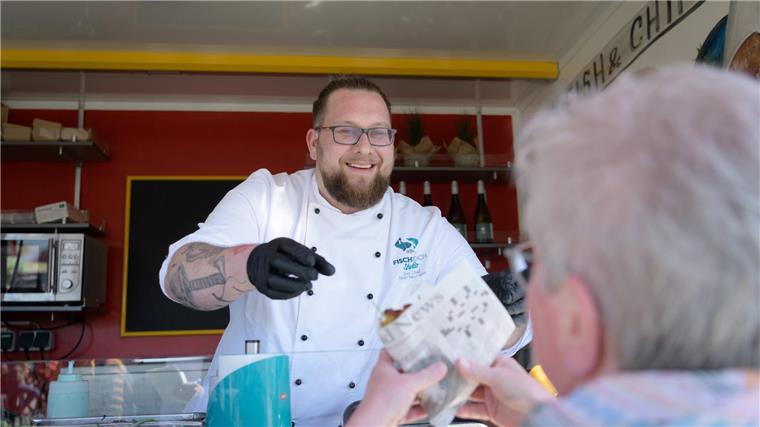 Hier ist Fisch in aller Munde: Besucher strömen zur Fischparty 2023 Fischburger, frisch zubereitet und mit guter Laune auf die Hand: Florian Neumann, Sous Chef des Seefischkochstudios, an ungewöhnlicher Wirkungsstätte - im eigens eingerichteten Foodtruck des Kochstudios. Foto: Masorat-f