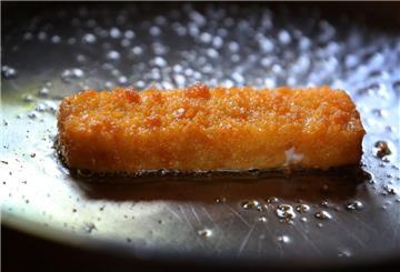 ILLUSTRATION - Ein Fischstäbchen wird in einer Pfanne gebraten. (Zu dpa "Fischstäbchen sollen teurer werden") (zu dpa: «Möglicherweise Kunststoff in Fischstäbchen – Rückruf»)