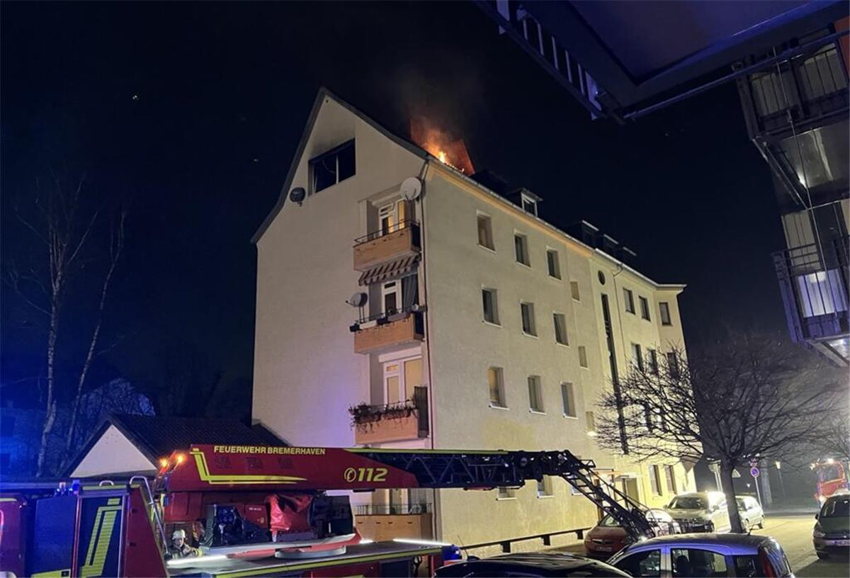 Offene Flammen aus dem Dachgeschoss eines vierstöckigen Hauses.