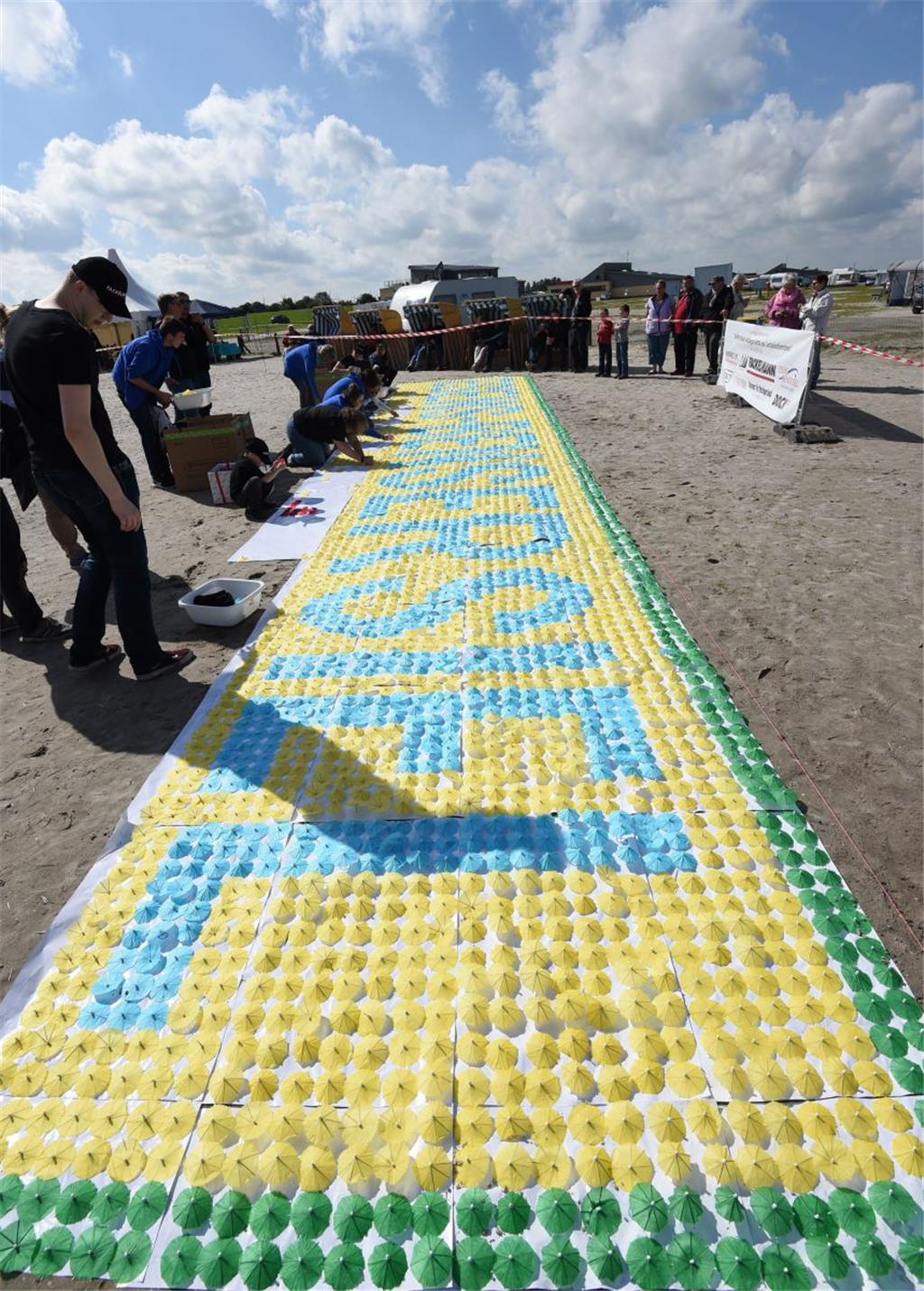 Freiwillige Helfer stecken am Strand von Bensersiel für einen Guinnessbuchrekord...