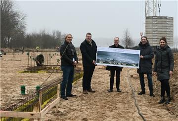 Eine Menschengruppe hält ein Plakat auf einer Baustelle hoch.