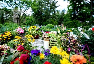 Eine Grableuchte und Blumen liegen auf einem Mühlstein in einem Gräberfeld auf dem Waldfriedhof