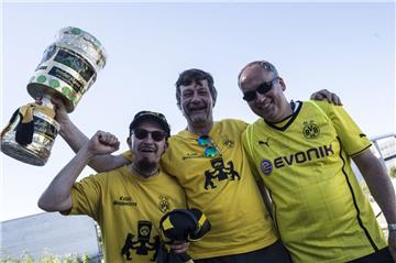 Für diese Dortmund-Fans ist das ergebnis schon klar: Sie üben mit einem DFB-Papppokal schon mal die Siegerpose.