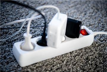 Die Netzstecker verschiedener Geräte sind in einem Wohnzimmer in eine Steckdosenleiste gesteckt.