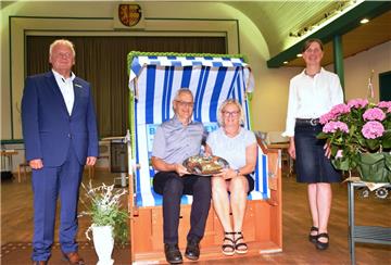 Für Ina Korter (Zweite von rechts) gab es viele Präsente, unter anderem einen Strandkorb und einen Kuchen in Butjadingen-Form. Das Foto zeigt zudem (von links) Landrat Thomas Brückmann, Ina Korters Lebensgefährten Henry Behm und Ratsvorsitzende Uta Meiners.