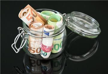 Mehrere Geldscheine stecken in einem Glas und ragen teilweise heraus. 