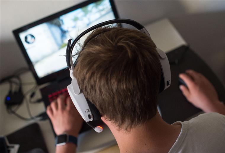 Ein Jugendlicher sitzt mit einem Headset vor einem Laptop
