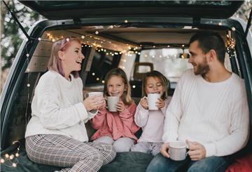 Eine Familie sitzt im weihnachtlich geschmückten Auto.