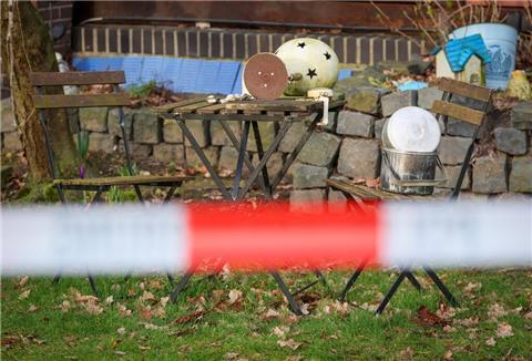 Gartendekoration steht hinter Absperrband der Polizei vor einem Haus in Westervesede in der Gemeinde Scheeßel, in dem am Vortag ein Mann zwei Personen erschossen haben soll.