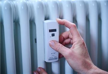 Eine Person stellt das Thermostat an der Heizung ein. 