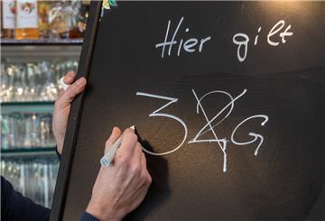 Gastronom Jörg Hicker passt eine Informationstafel in der «Ansprechbar» an. Ab dem 04.03.2022 gilt in der bayerischen Gastronomie die 3G-Regel. +++ dpa-Bildfunk +++