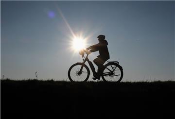 Gegen die Sonne fotografiert sieht man die Silhouette eines Fahrradfahrers.