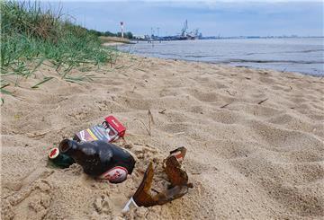 Glasflaschen und eine Zigarettenschachtel liegen am Nordenhamer Weserstrand im Sand.