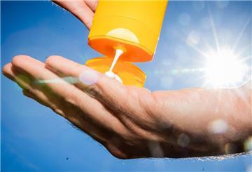 Sonnencreme wird aus der Tube auf eine Hand gedrückt