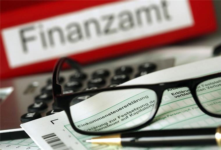 Mehr Geld vom Finanzamt: Diese 5 Steuertipps kennen die wenigsten Eine Brille liegt auf der Einkommenssteuererklärung. Im Hintergrund steht Finanzamt.