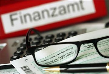 Eine Brille liegt auf der Einkommenssteuererklärung. Im Hintergrund steht Finanzamt. 
