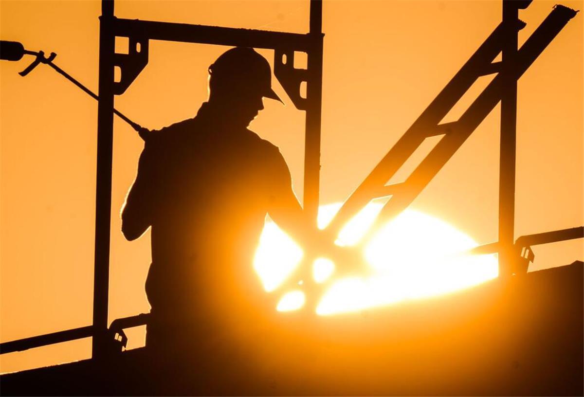Berufskrank? Warten kann die Rente kosten! Mann auf Gerüst vor Sonnenuntergang