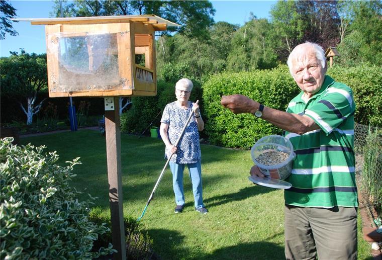 Gerhard Otto bestückt das Vogelhäuschen auf "Parzelle 34" mit frischem Futter, seine Frau Erika hat zur Harke gegriffen.