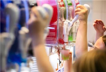 PRODUKTION - 23.01.2024, Berlin: Kinder befüllen ihre Becher bei einem Kindergeburtstag mit Slush-Eis in verschiedenen Geschmackssorten. (zu dpa: «Studie: Schon Kleinkinder essen zu süß und ungesund») Foto: Christoph Soeder/dpa +++ dpa-Bildfunk +++